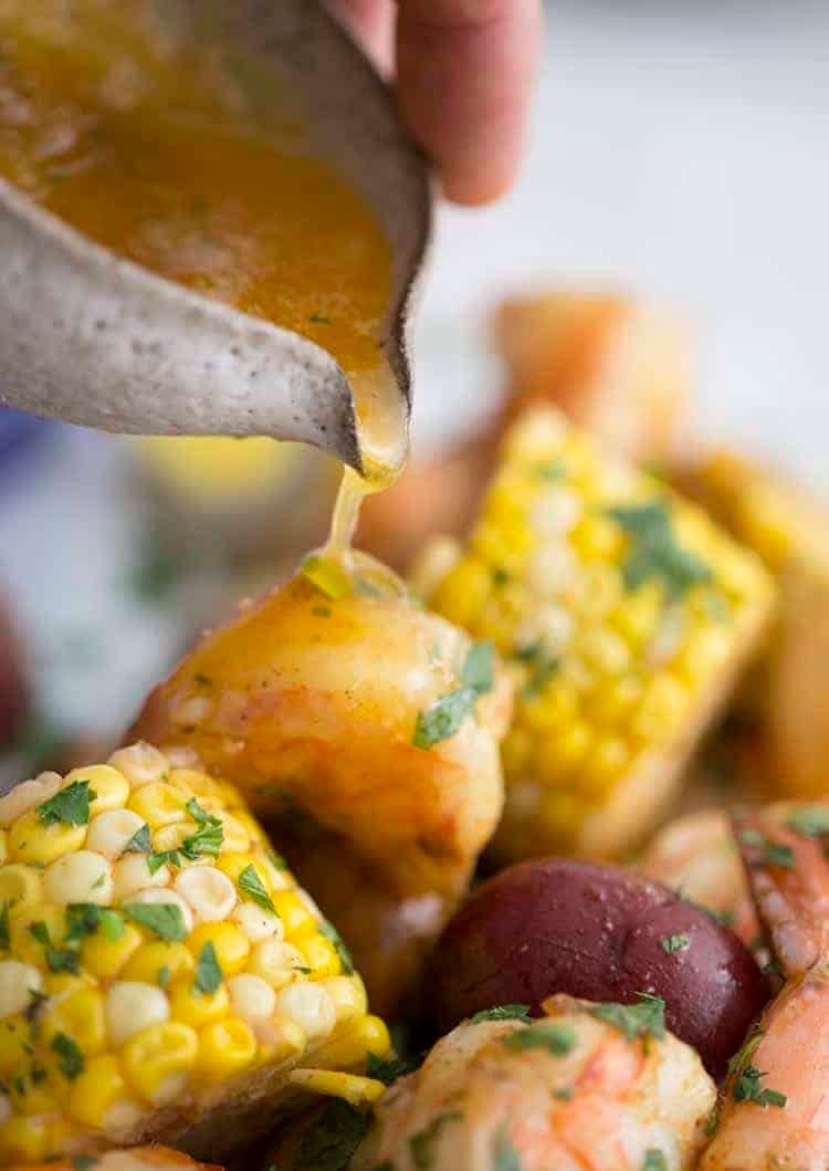Seasoned melted butter being poured onto a shrimp boil