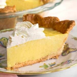 a piece of vanilla cream pie topped with whipped cream on a porcelain plate