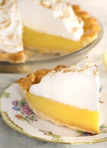 A slice of lemon meringue pie on a porcelain plate.