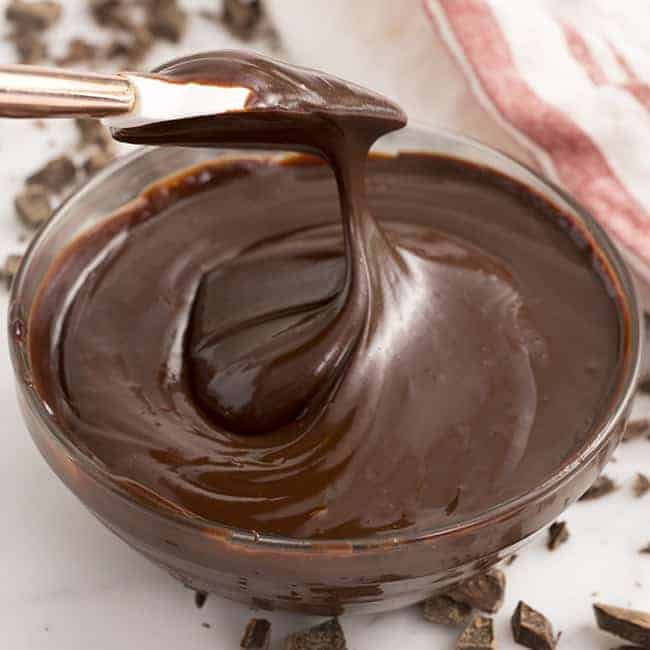 a bowl of chocolate ganache being swirled with a spatula