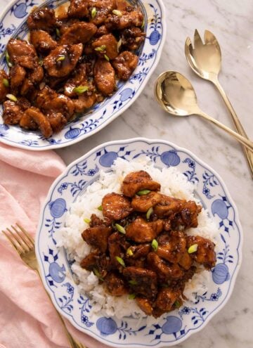 An overhead shot of Bourbon Chicken on a blue plate with rice