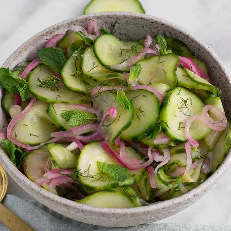 Cucumber salad with red onion, dill and mint in a bowl.