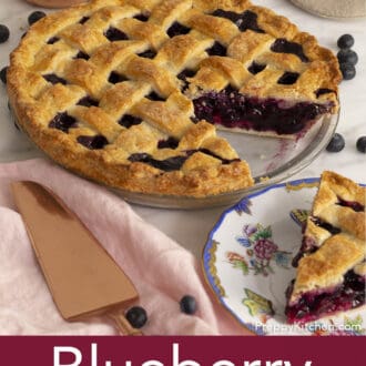 blueberry pie in background with a piece of pie on plate