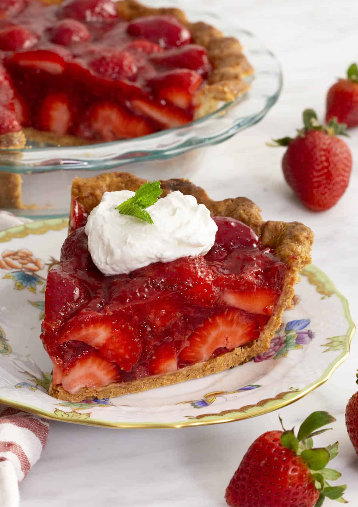 A piece of strawberry pie on a porcelain plate.