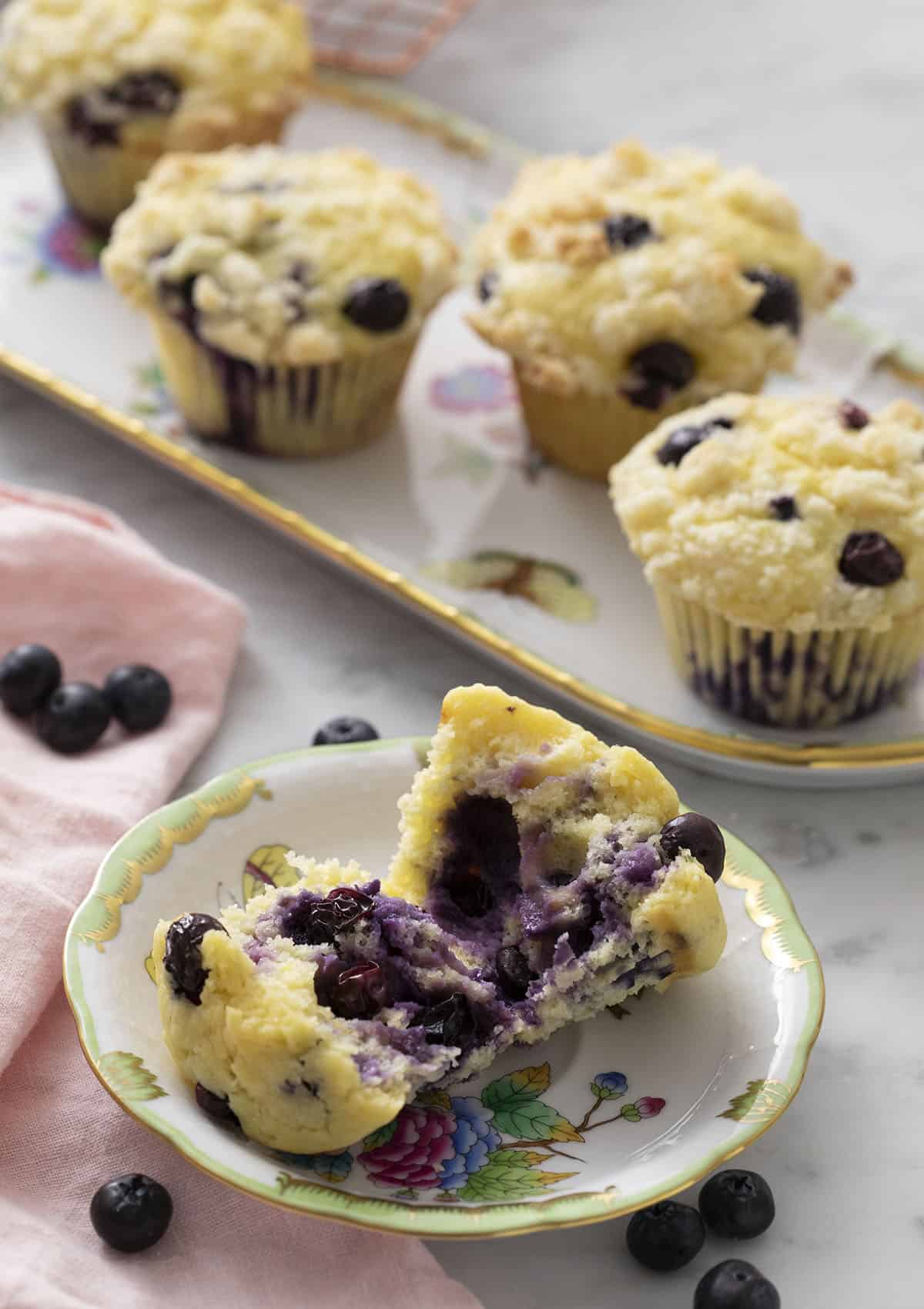 A blueberry muffin torn in half revealing a berry-filled interior.