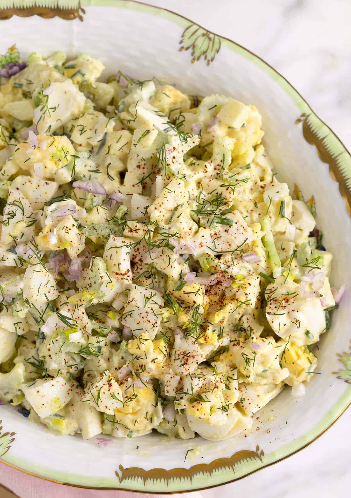 Egg salad sprinkled with fresh dill in a porcelain bowl.