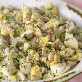 Egg salad topped with fresh herbs in a porcelain serving bowl.