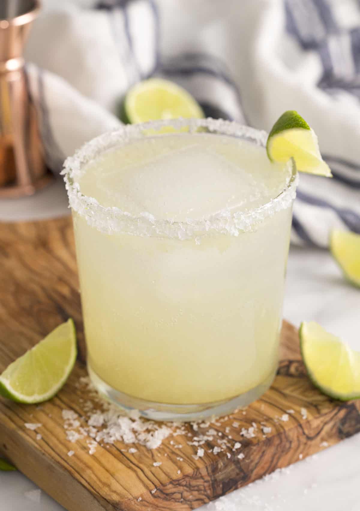 A scratch margarita in a tumbler garnished with a lime wedge.