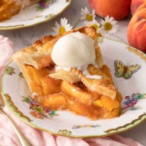 A piece of peach pie with a scoop of vanilla ice cream on top.