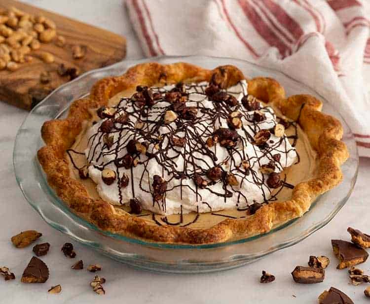 A chocolate peanut butter pie with whipped cream and chocolate covered peanuts