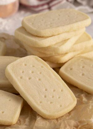 A group of shortbread cookies. some are stacked while others are on crumpled paper.