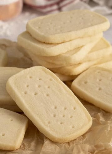 A group of shortbread cookies. some are stacked while others are on crumpled paper.