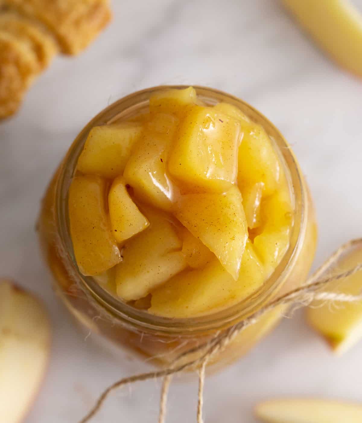 A top-down view of apple pie filling in a glass jar.