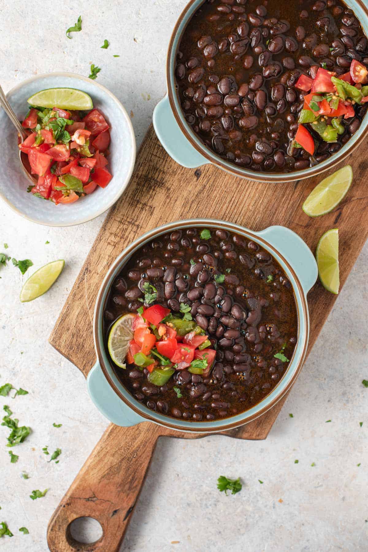 An overhead shot of black beans and salsa in two blue dishes