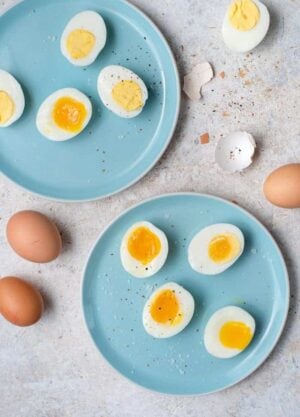 An overhead shot of hard boiled eggs and soft boiled eggs on two blue plates.