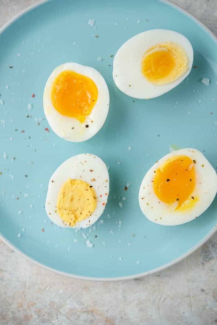 An overhead shot of instant pot hard boiled eggs and soft boiled eggs on a blue plate