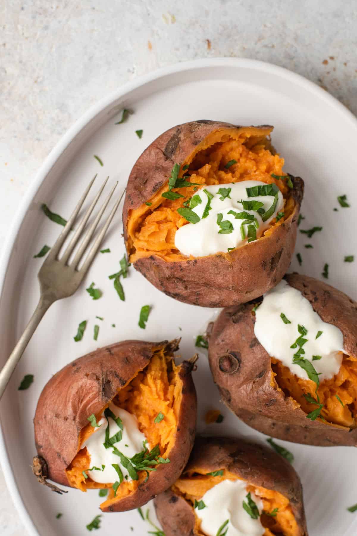 A close up of sweet potatoes topped with sour cream and herbs