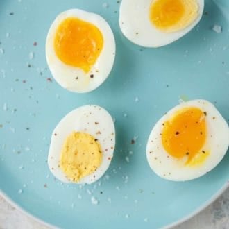 A close up view of cut Instant Pot hard boiled eggs of different doneness on a blue plate topped with salt and pepper.