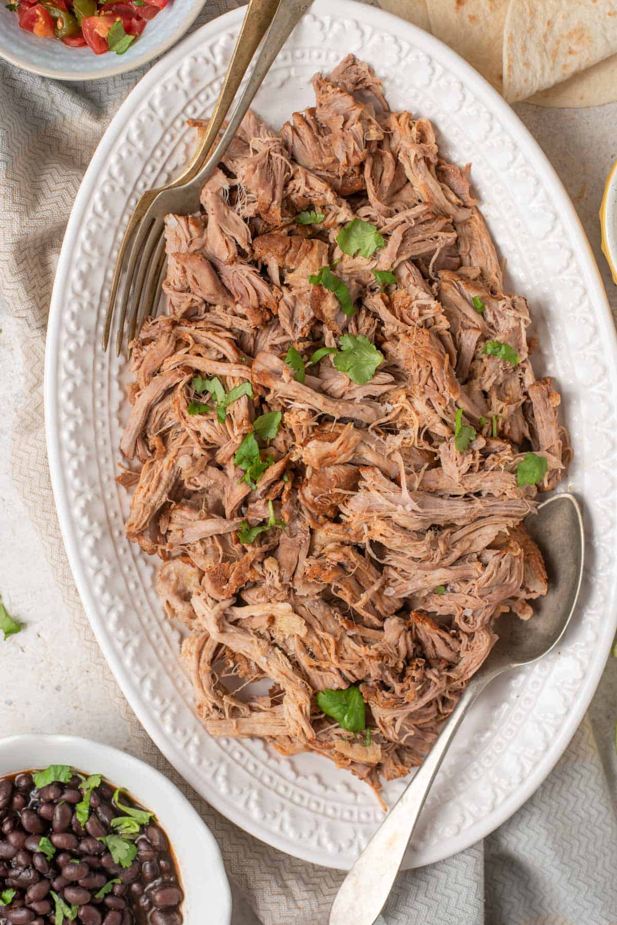 An overhead shot of pulled pork on a white serving platter