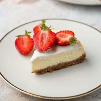 A plate with a slice of Instant Pot cheesecake topped with cut strawberries.