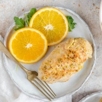 An overhead view of a plate with an Instant Pot chicken breast with sliced oranges with a fork on the side.