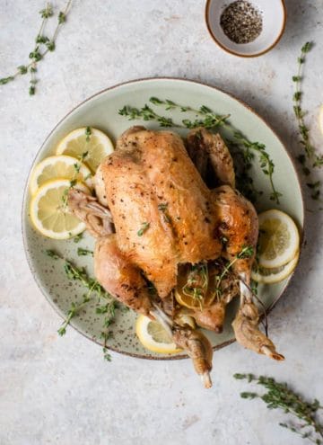 An overhead shot of an instant pot whole chicken on a plate with lemon and thyme
