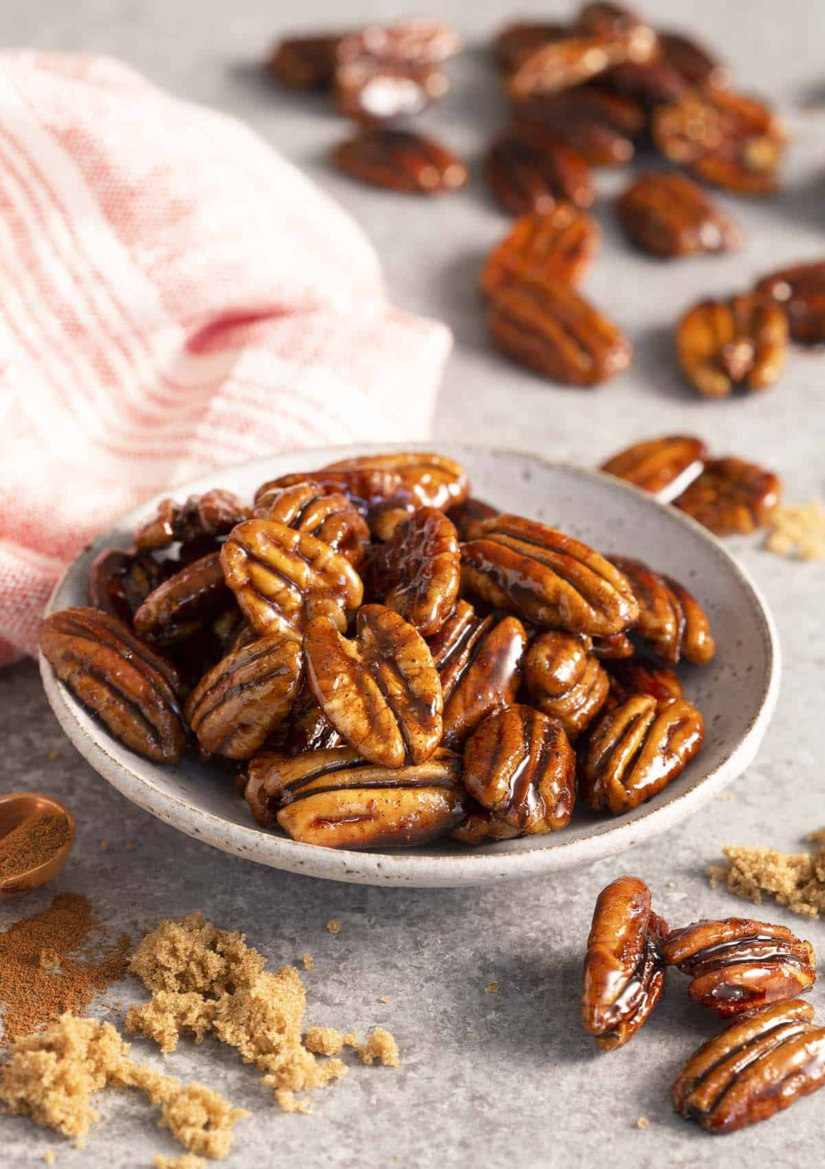 A plate of candied pecans next to some brown sugar.
