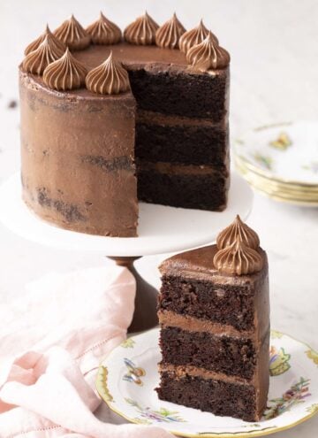 A three layer zucchini chocolate cake sitting on a cake stand