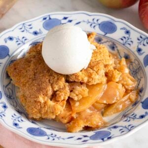 Apple cobbler on a plate with a scoop of vanilla ice cream.