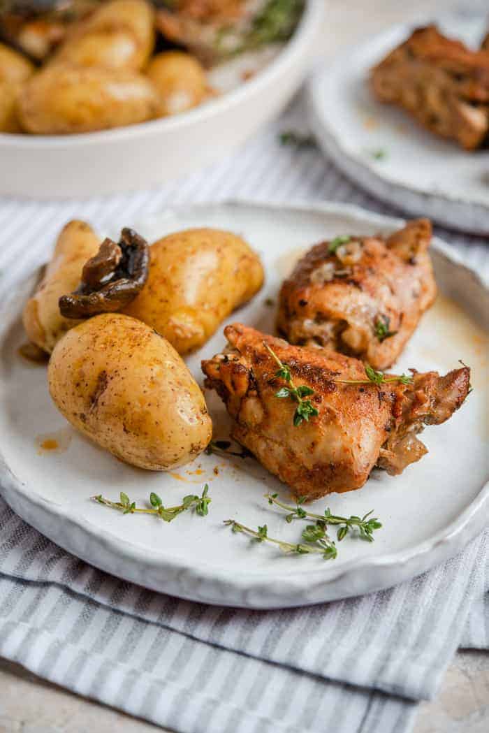 A side shot of instant pot chicken thighs and potatoes on a rustic plate