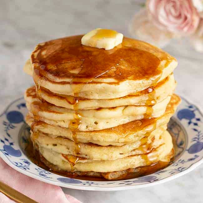 A giant stack of pancakes covered in maple syrup and butter