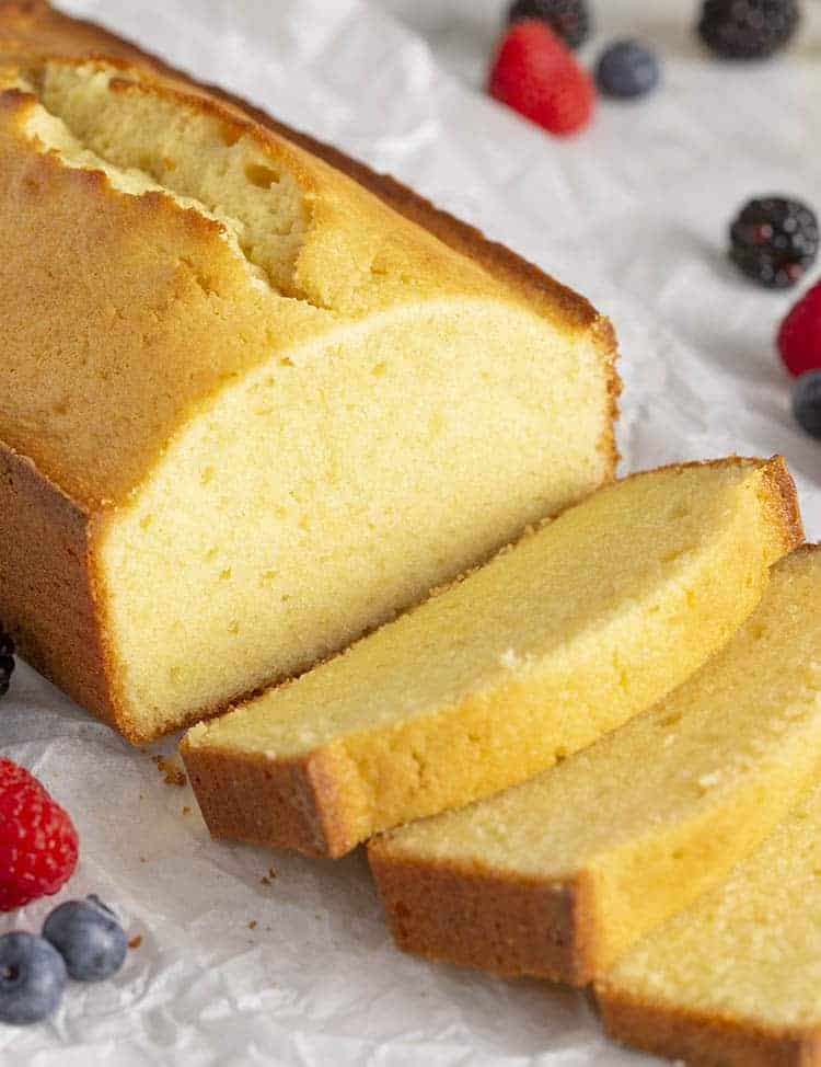 A loaf of pound cake cut into slices on a white marble table