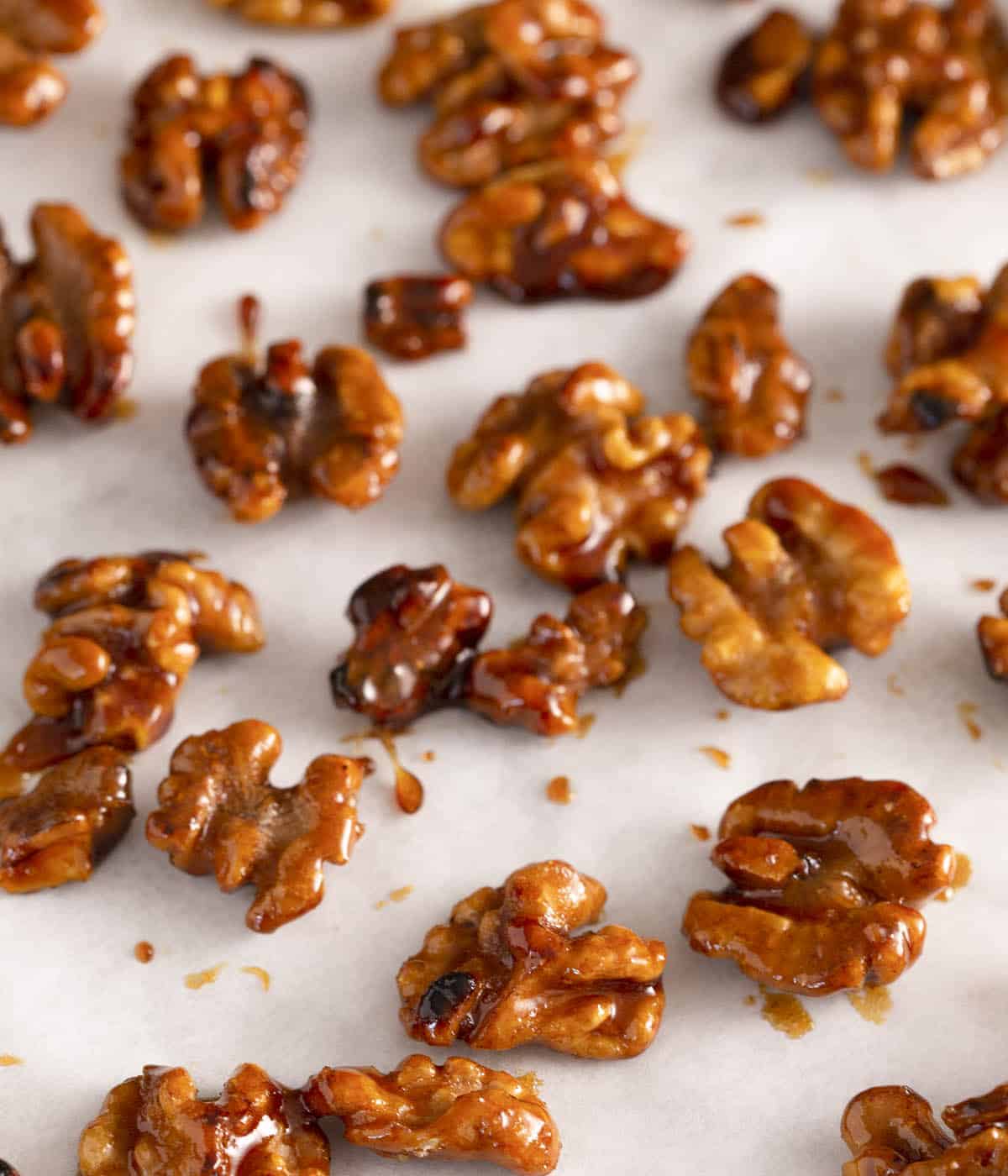 Candied walnuts spread out on a sheet of white parchment paper.
