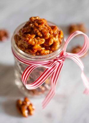 Candied walnuts in a mason jar with a red and white bow