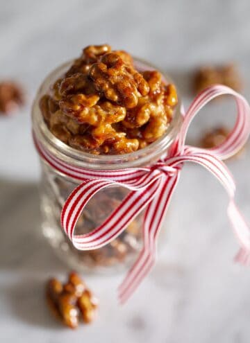 Candied walnuts in a mason jar with a red and white bow