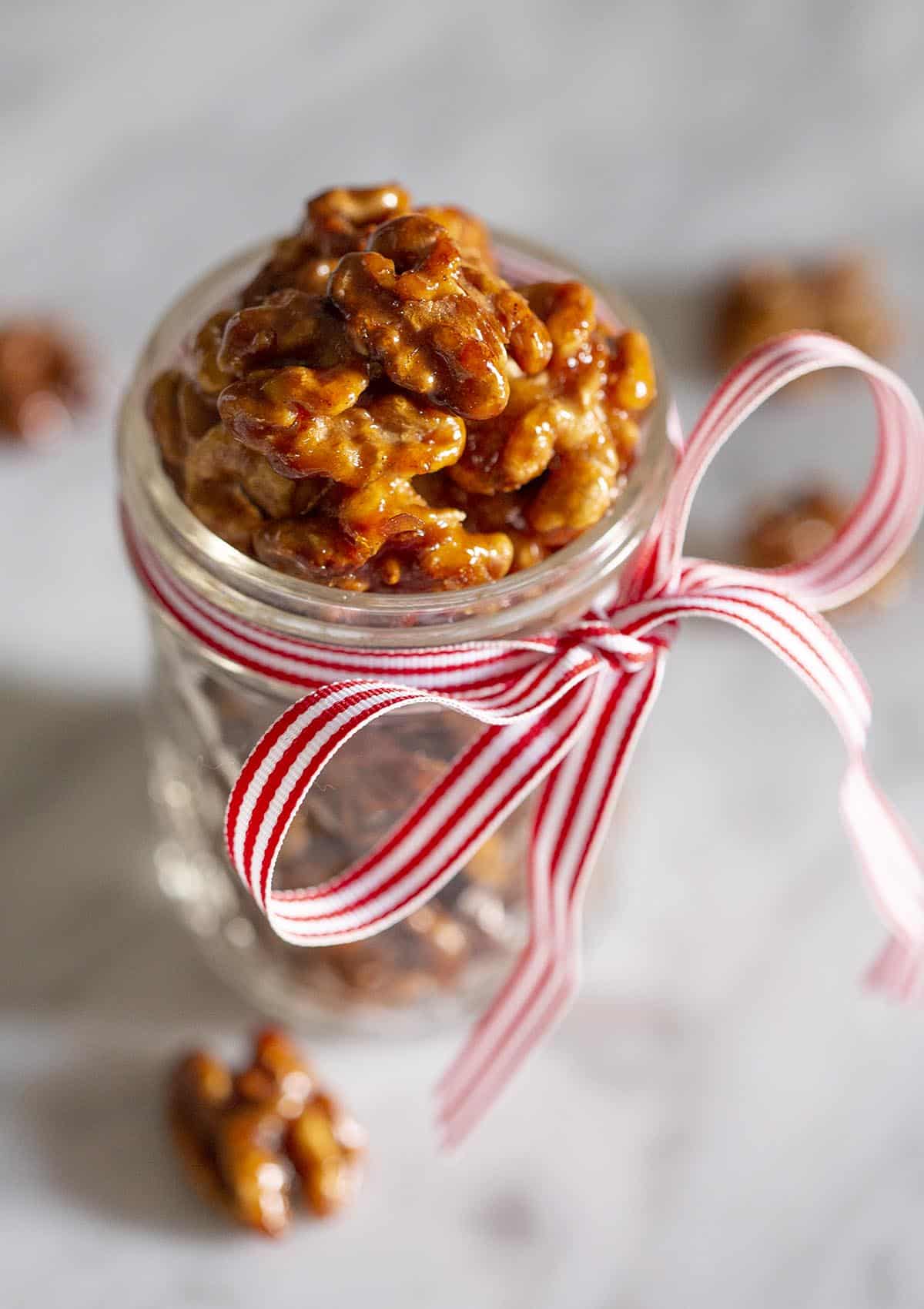 Candied walnuts in a mason jar with a red and white bow