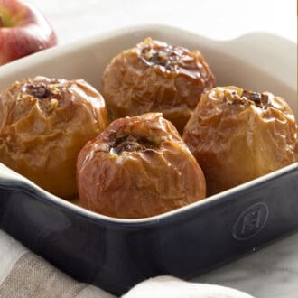 Four baked apples in a blue baking dish.