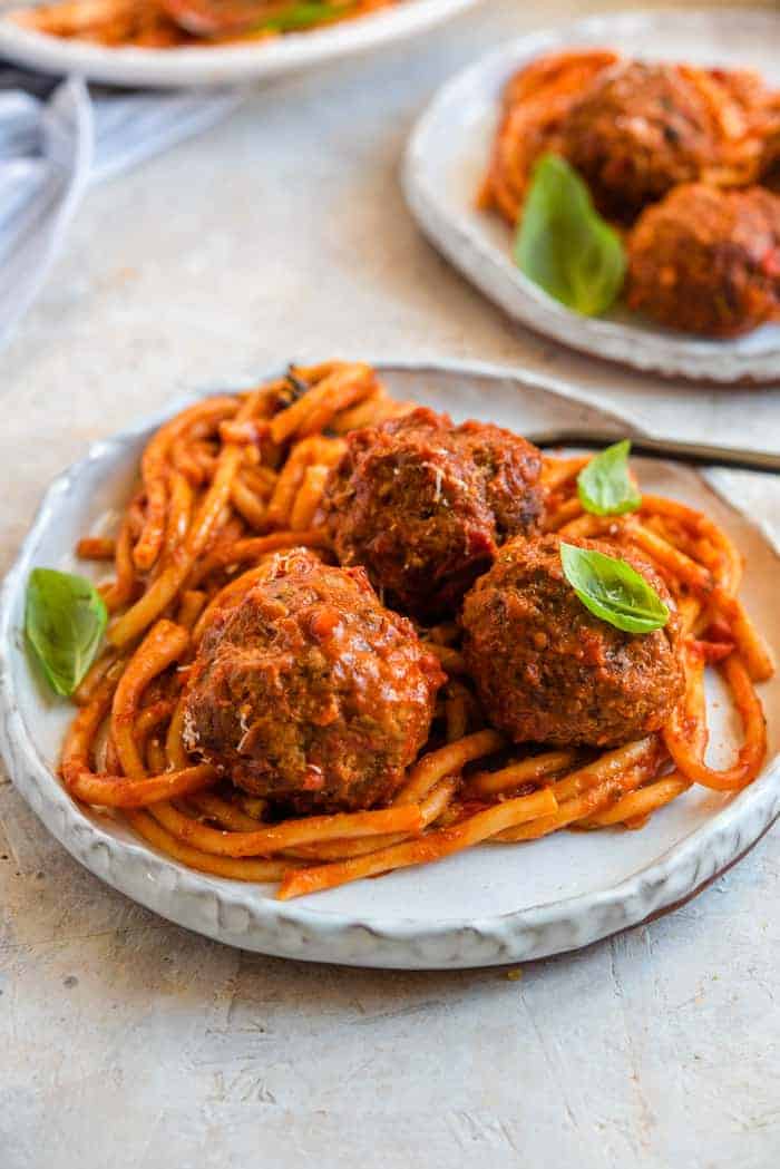 Instant pot spaghetti and meatballs on a rustic plate topped with fresh basil