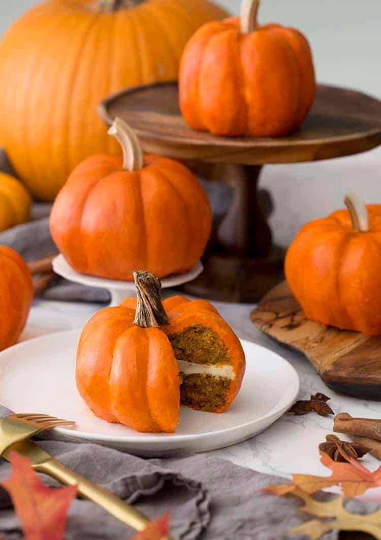 A group of small cakes that look exactly like orange pumpkins.