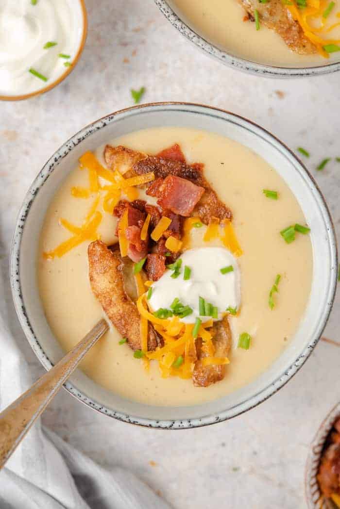 An overhead shot of potato soup in a bowl topped with bacon and cheese
