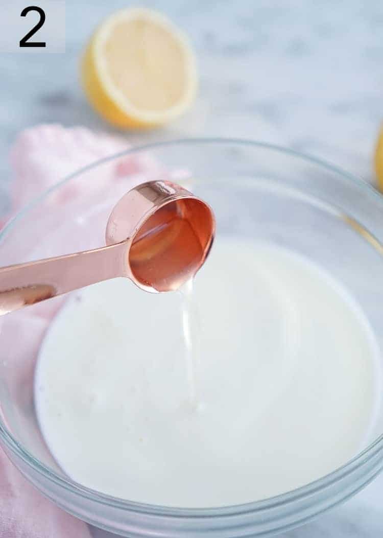 Lemon juice being poured into a bowl of milk.