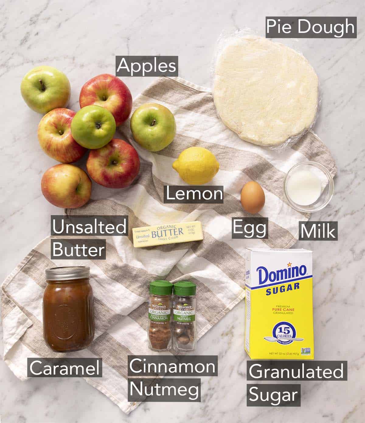 Ingredients to make mini apple pies on a marble counter.