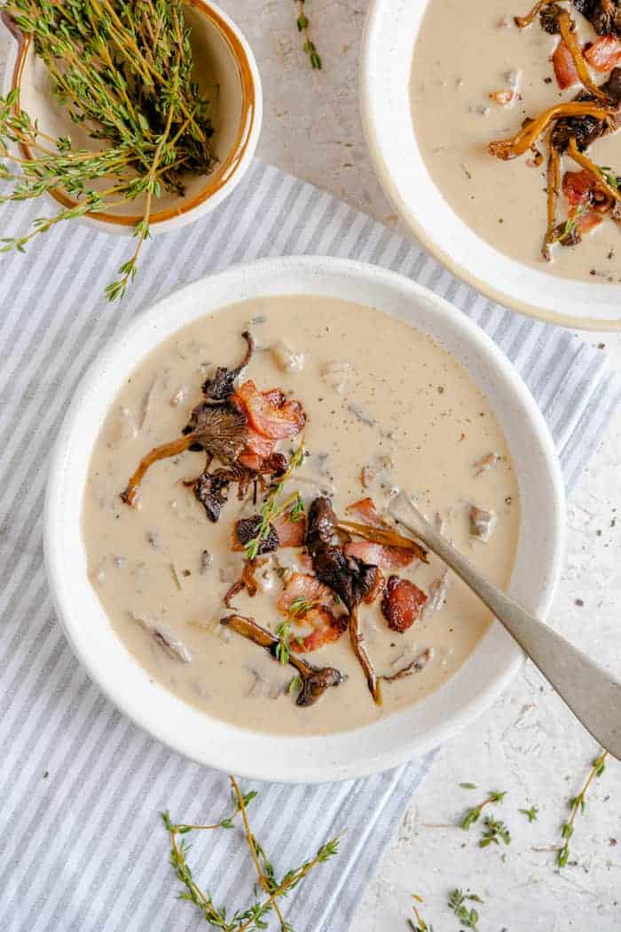 Cream of mushroom soup topped with thyme and bacon in a bowl