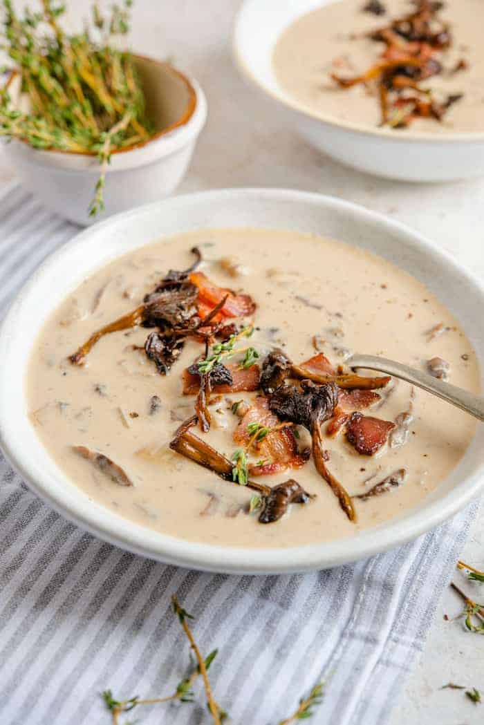 A side shot of cream of mushroom soup topped with mushrooms and bacon