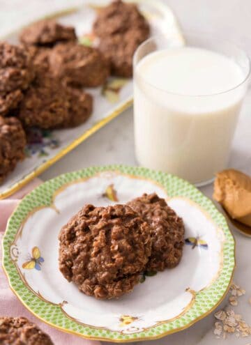 No bake cookies on a plate with a glass of milk behind it