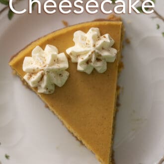 A piece of pumpkin cheesecake with two dollops of whipped cream on a white plate.