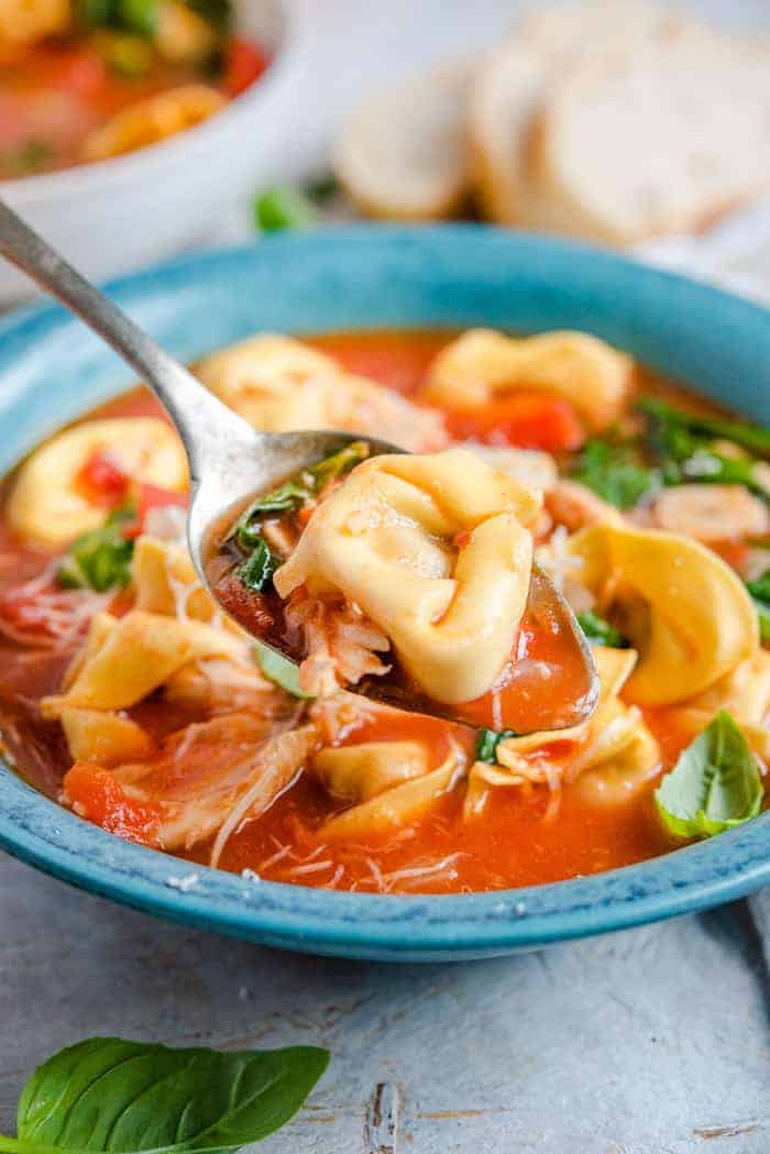 A close up of a spoonful of tortellini soup