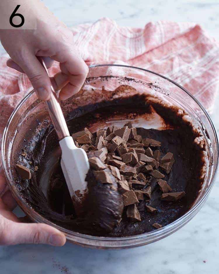 Chocolate pieces getting folded into brownie batter.