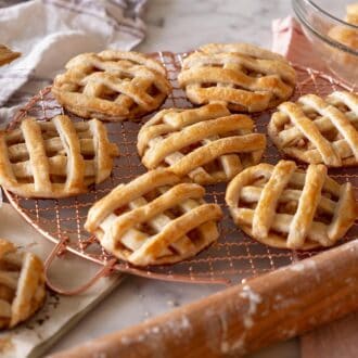 Mini apple pies on a copper cooling rack.