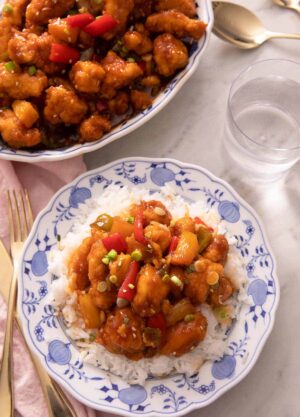 An overhead shot of sweet and sour chicken and rice on a blue plate